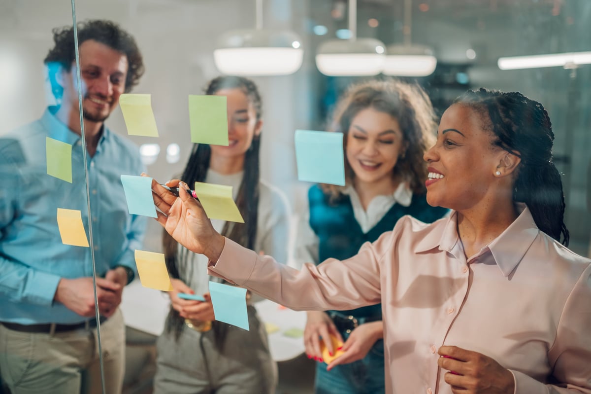 Team collaborating on a project using sticky notes on a glass wall